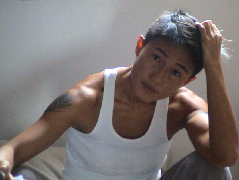 An androgynous person with short hair, and muscular arms looking at the camera.