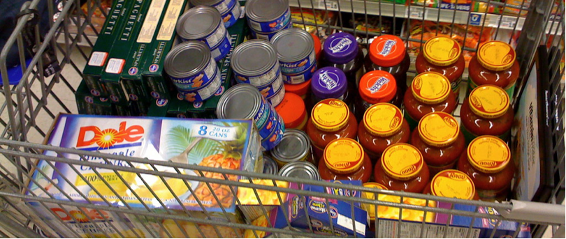 Shopping cart full of cans, spaghetti sauce, pasta and other bulk goods.