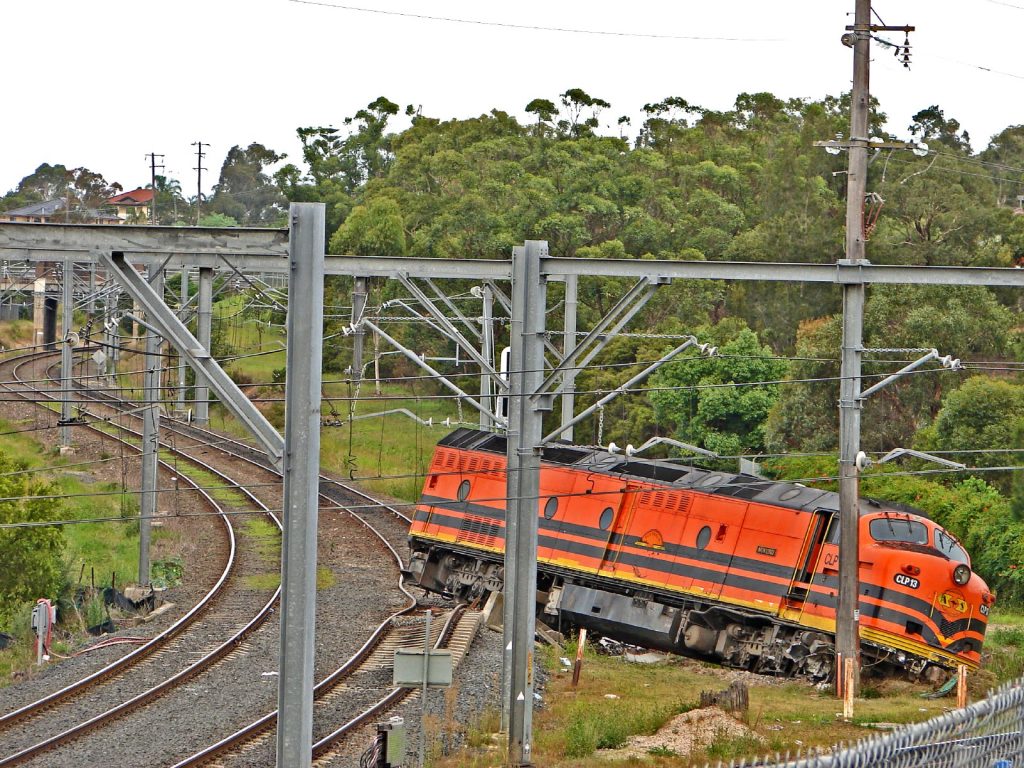 Image of an orange train going off the tracks.