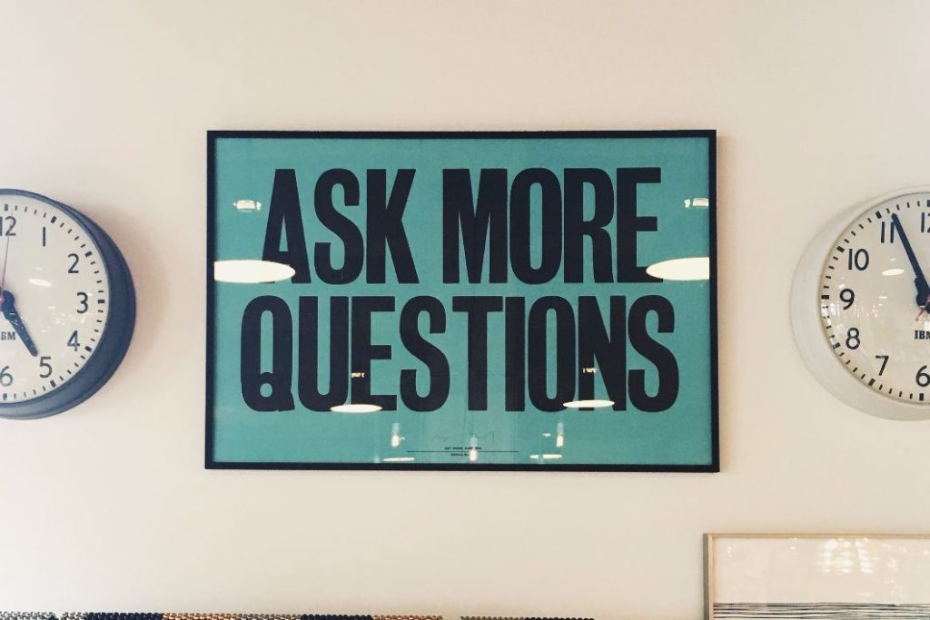 poster on a wall that reads "ask more questions"